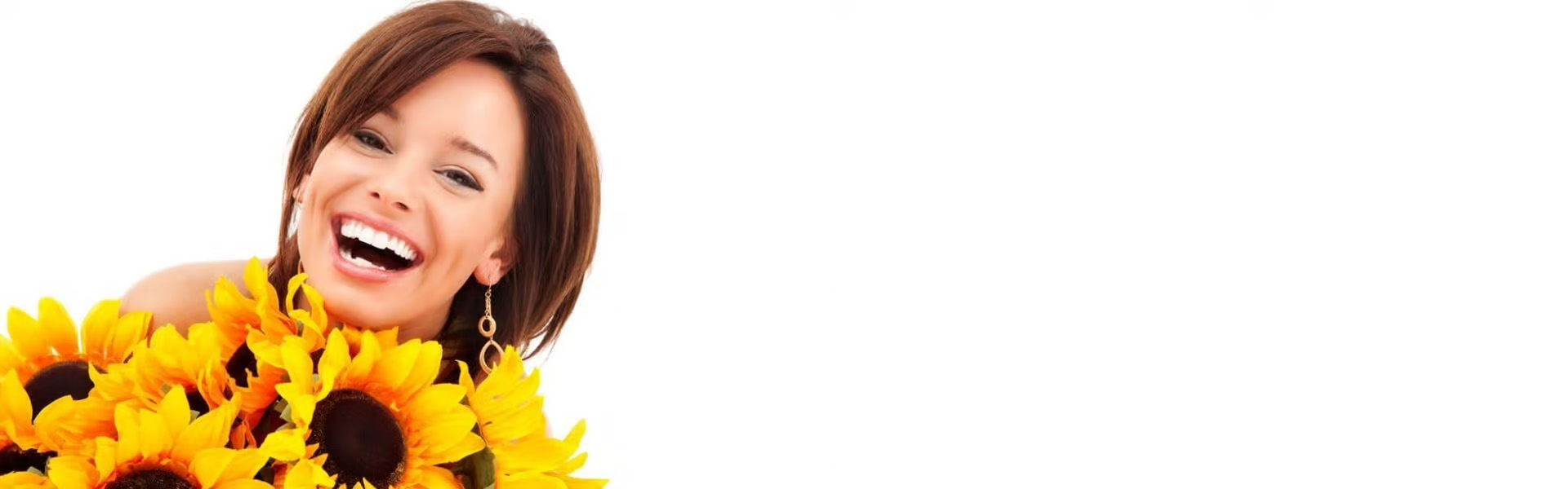 The image shows a woman smiling at the camera with sunflowers in front of her face.