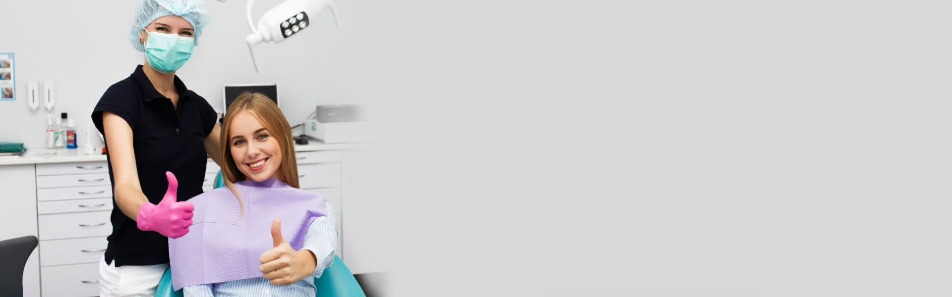 The image shows two individuals in a dental office setting, with one person giving a thumbs-up gesture while sitting in a dentist s chair, and another standing behind them, also smiling and holding up their thumb.